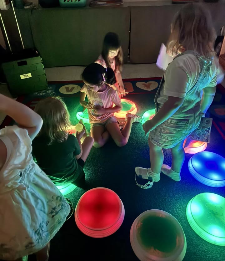 Children playing around glowing stones on a classroom rug