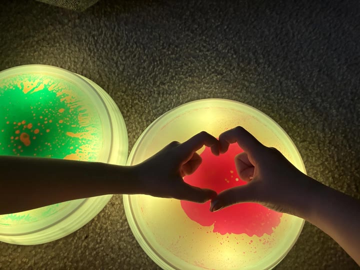 Hands making a heart shape over two glowing liquid stones