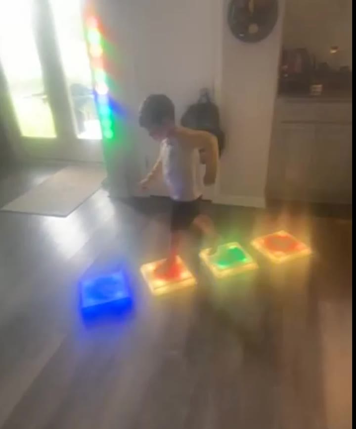 A child hopping across glowing squares in a kitchen