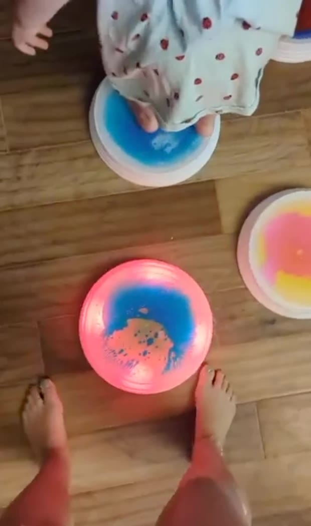 Bare feet next to a glowing liquid stone on a wooden floor